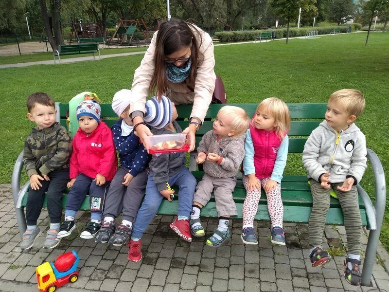 Dzieci siedzące na ławce w ogrodzie żłobka